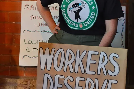 Photo credit: desrowVISUALS/ChrisGoodwin Organizer Len Harris stands with sign reading Workers Deserve Fair Wages