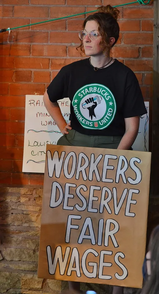 Photo credit: desrowVISUALS/ChrisGoodwin Organizer Len Harris stands with sign reading Workers Deserve Fair Wages